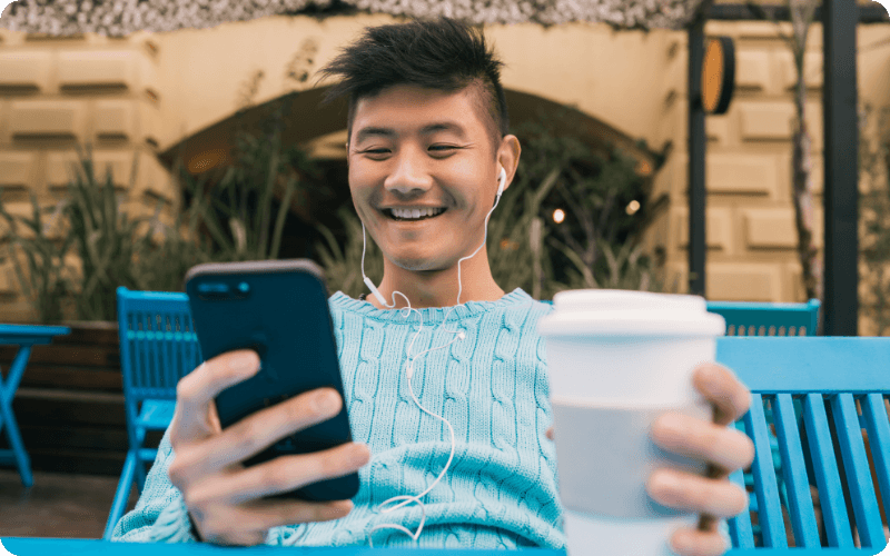 man using his mobile while drinking coffee