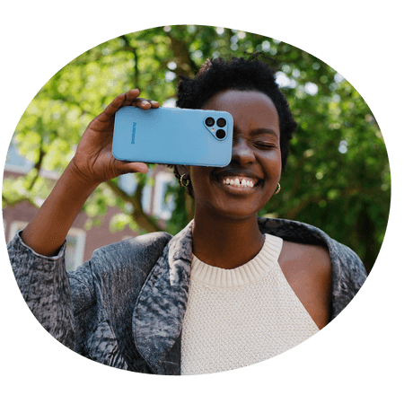 woman holding a blue Fairphone 5 up to her face