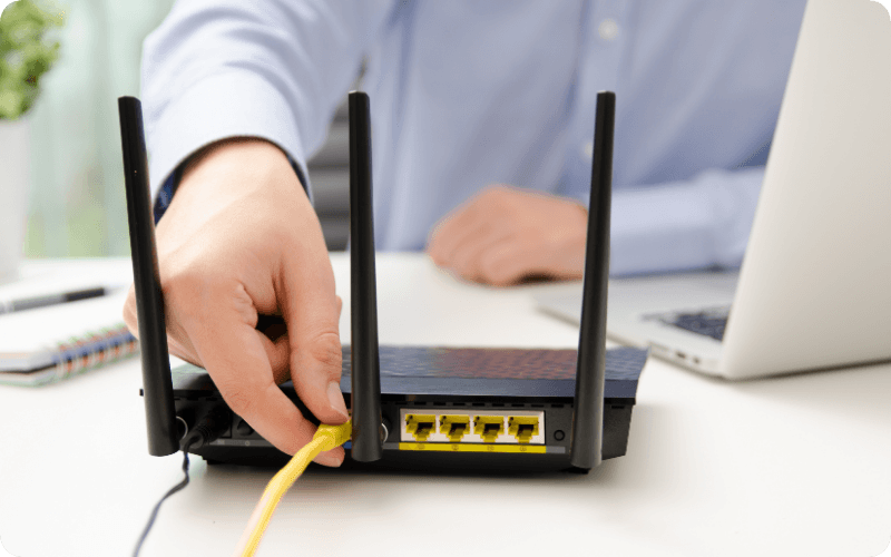 person plugging in their LAN cable into the router