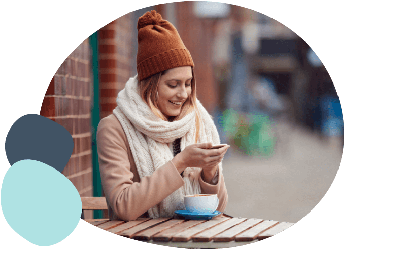 woman sat outside a coffee shop with her mobile