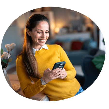 woman leaning on a counter using her iPhone