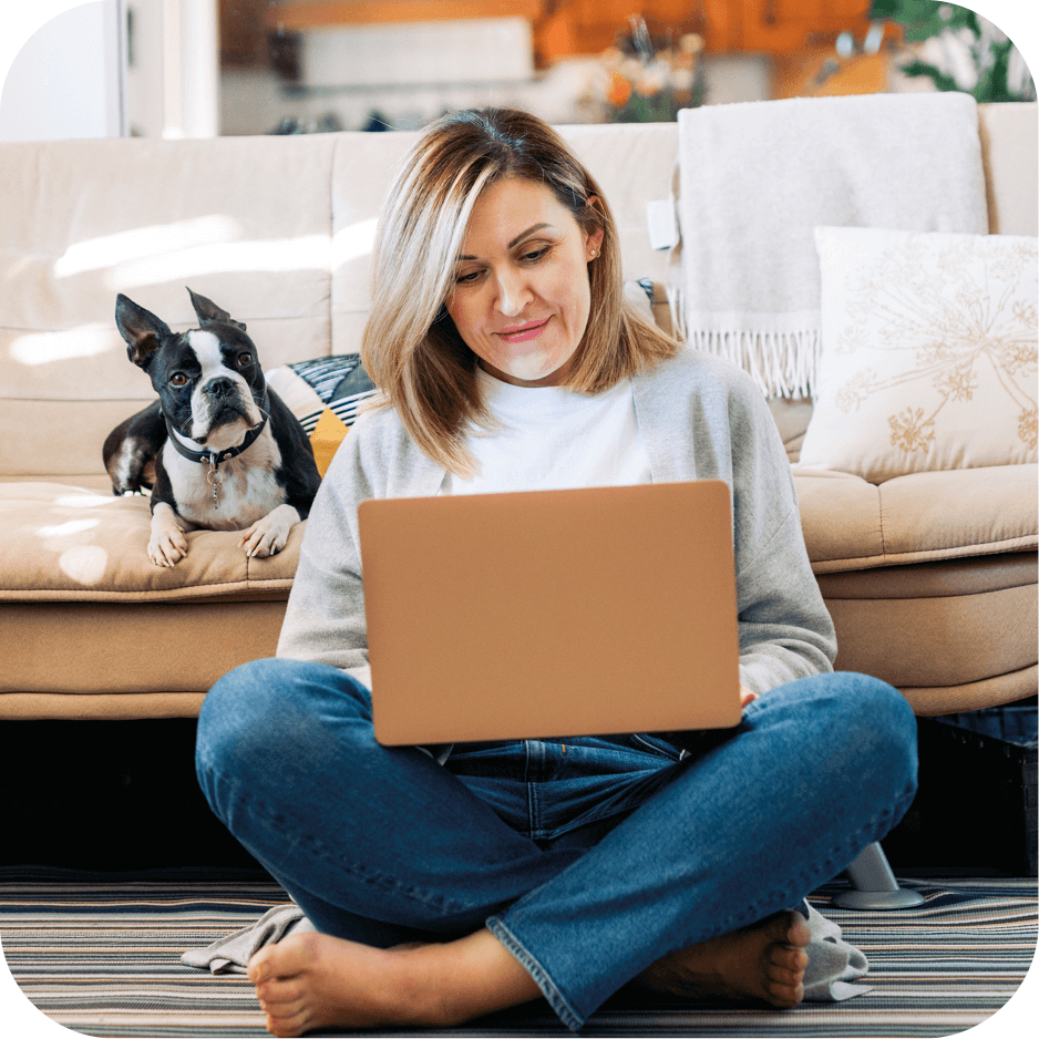 woman using a laptop with her dog next to her