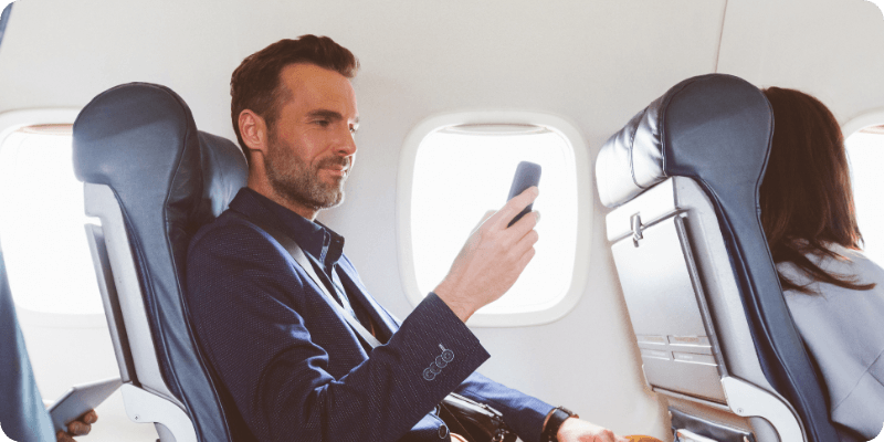 man using his mobile on a plane