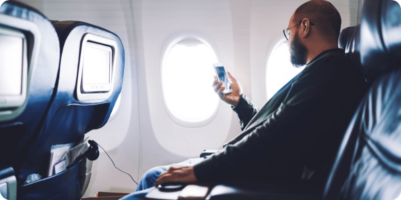 man using his mobile on a plane
