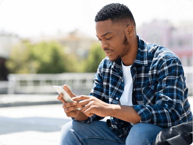 young man sat outside checking his mobile