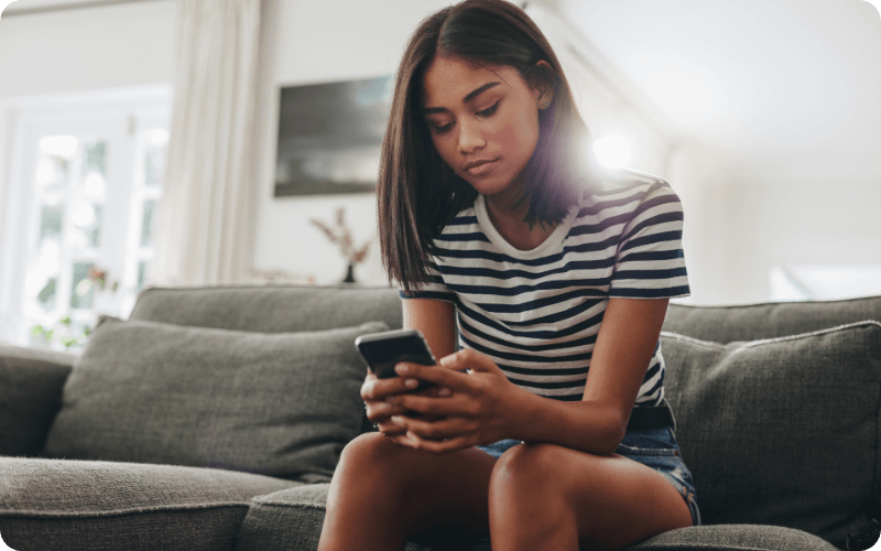 young woman sat at home checking her phone