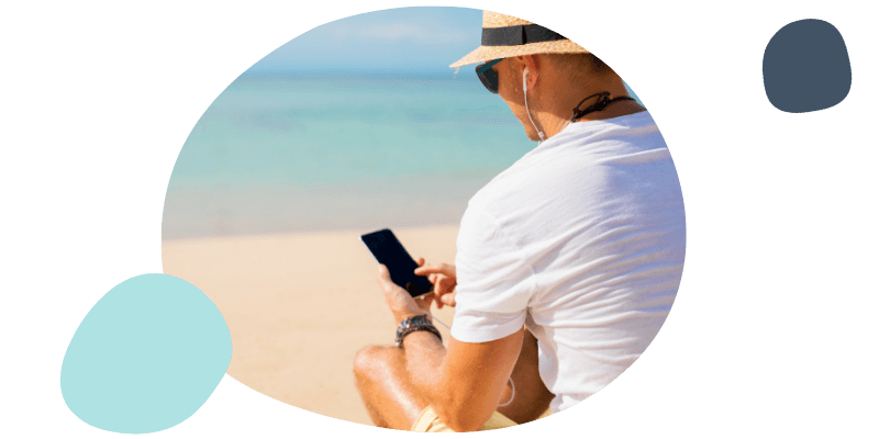 man using his phone at the beach on holiday