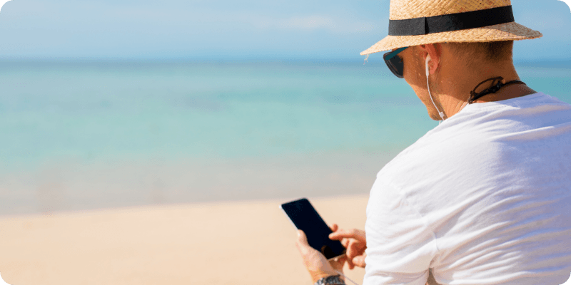 man using his phone at the beach on holiday