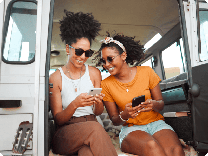 two friends using their mobile on holiday