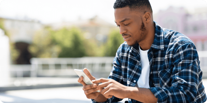 man texting his friends outside