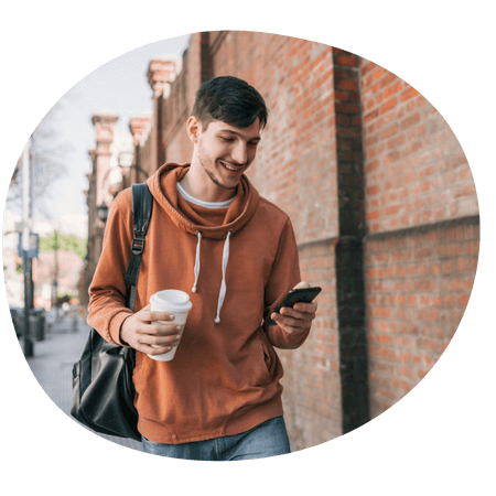 man holding a coffee whilst using his phone