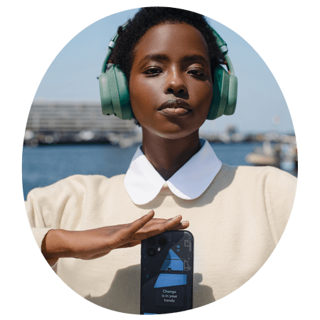 woman holding a fairphone whilst wearing fairbuds xl headphones