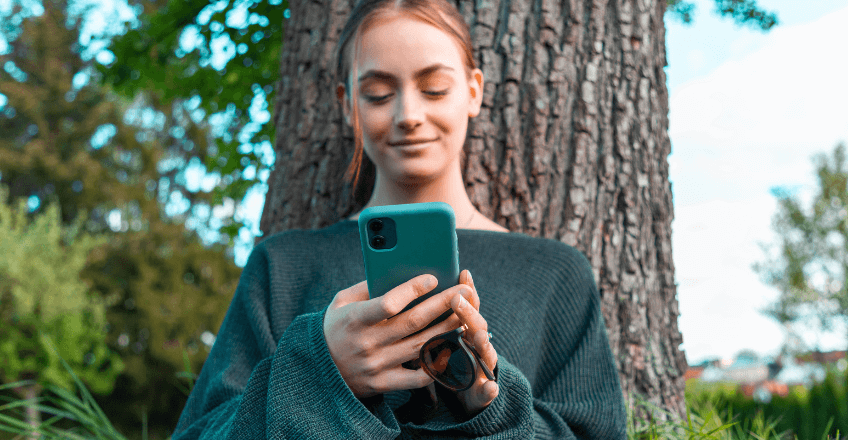 Woman smiling at her phone in nature