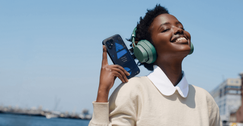 woman using her fairphone 5 whilst wearing Fairbuds XL headphones