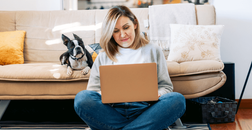 woman browsing the web with a dog next to her on a chair