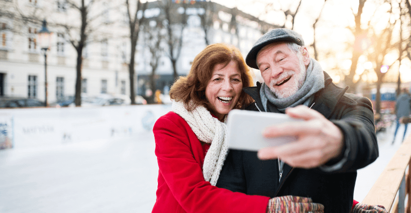 elderly couple taking a picture with their phone