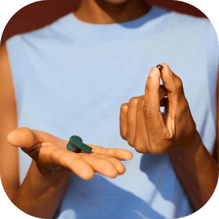 woman wearing green Fairbuds XL headphones outside