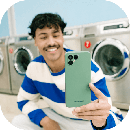 Man using his fairphone at a laundromat