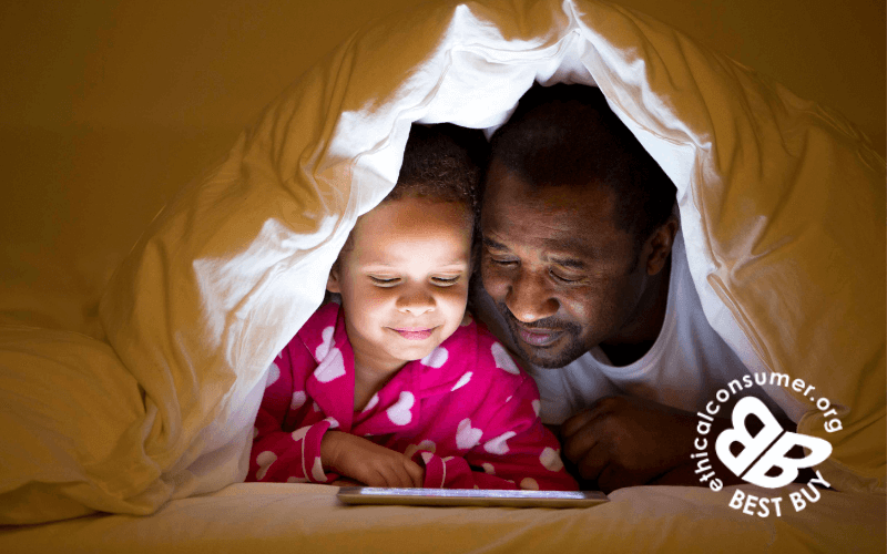 Grandad and grandchild under a duvet tent watching a film on ipad
