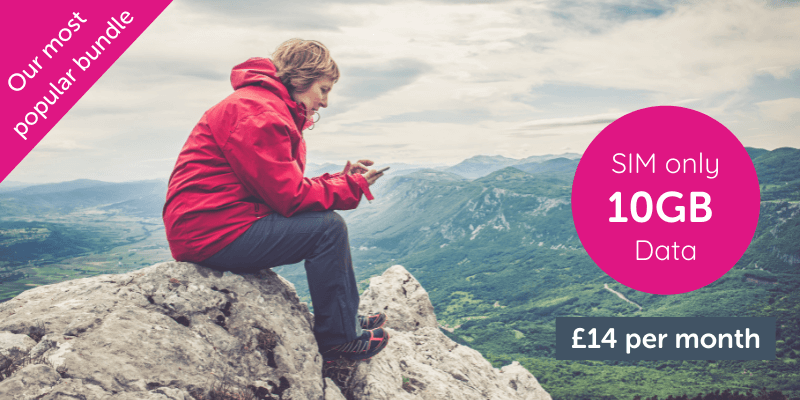 Woman sat on a mountain whilst hiking using her smartphone