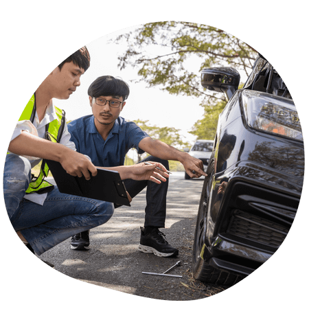 2 men inspecting car on the side of a road